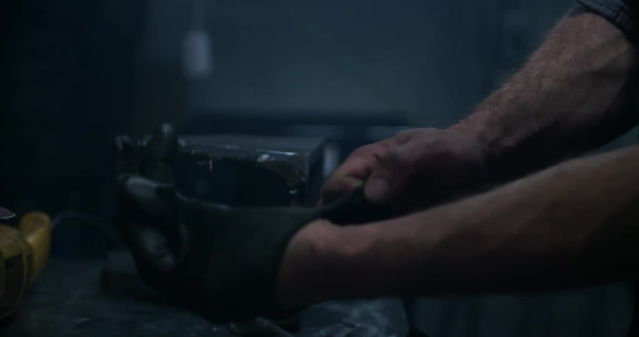 A man is standing and putting on gloves