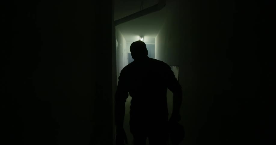 A person walks down a dark hallway