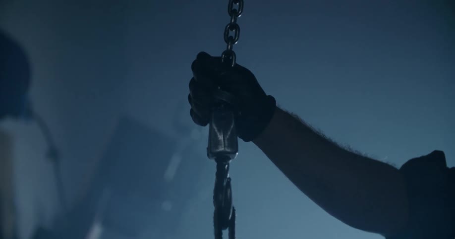 A man guides a hook into the air in a warehouse