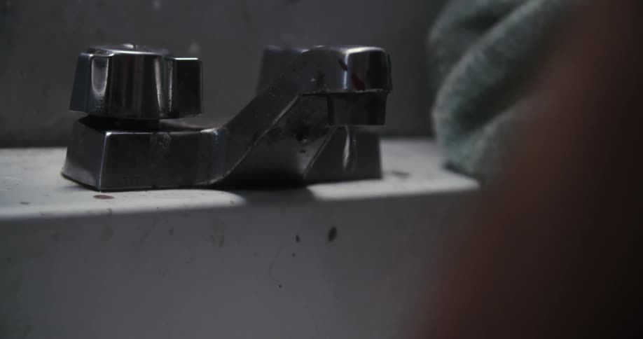 Water drips from a dingy bathroom faucet