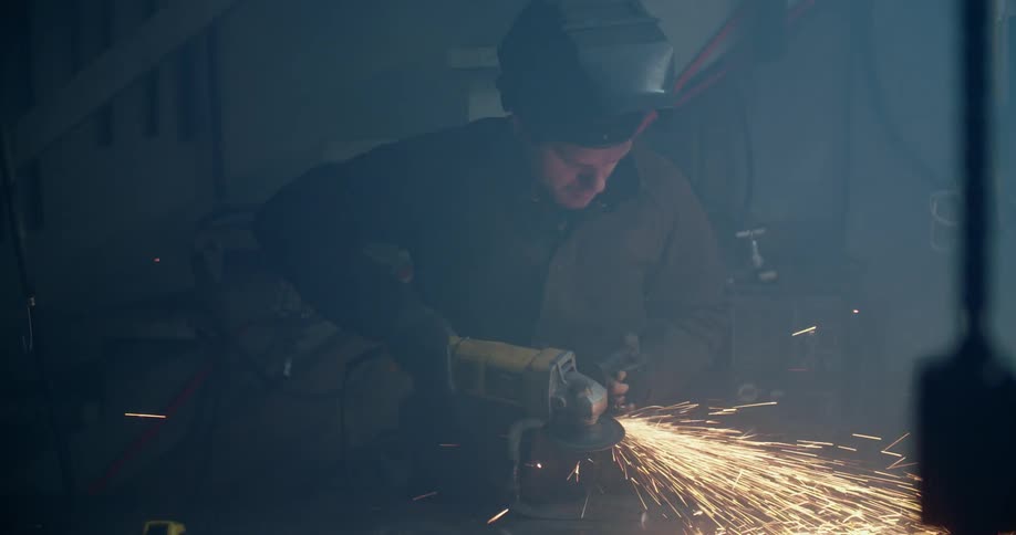 A welder uses a grinder on a piece of metal
