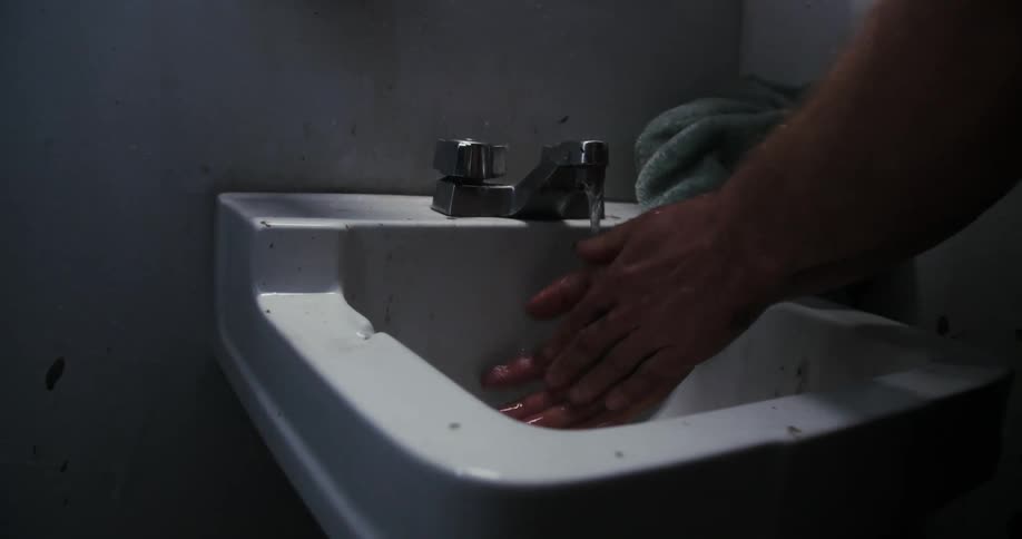 A man washes his hands at a bathroom sink