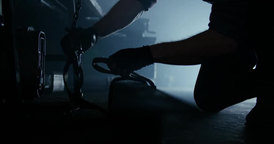 A man connects a strap to a large hook
