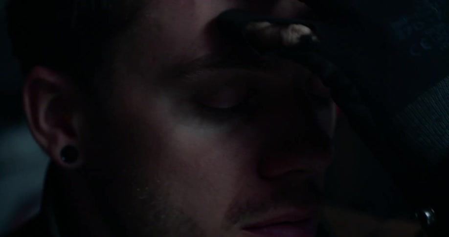 A man rubs his hand through his hair as he concentrates