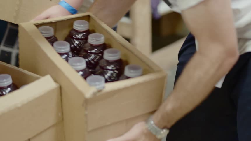 Store workers moving boxes containing juice bottles