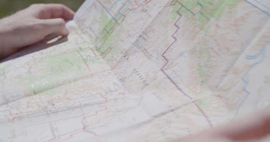 Hands unfolding and laying out a travel map