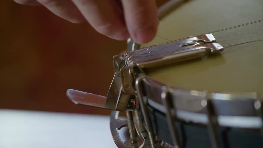 Man threads a wire onto a banjo
