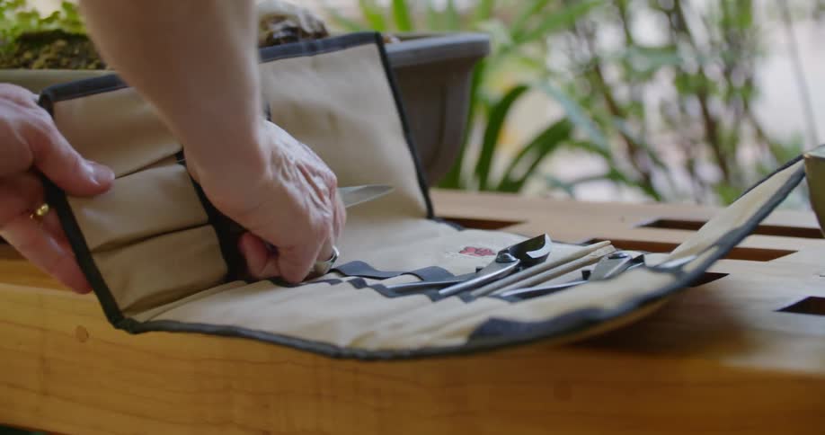 Person opening canvas organizer on table then pulling garden trimmers out