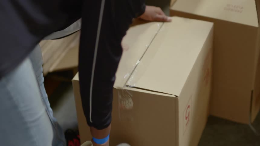 A man tapes up boxes