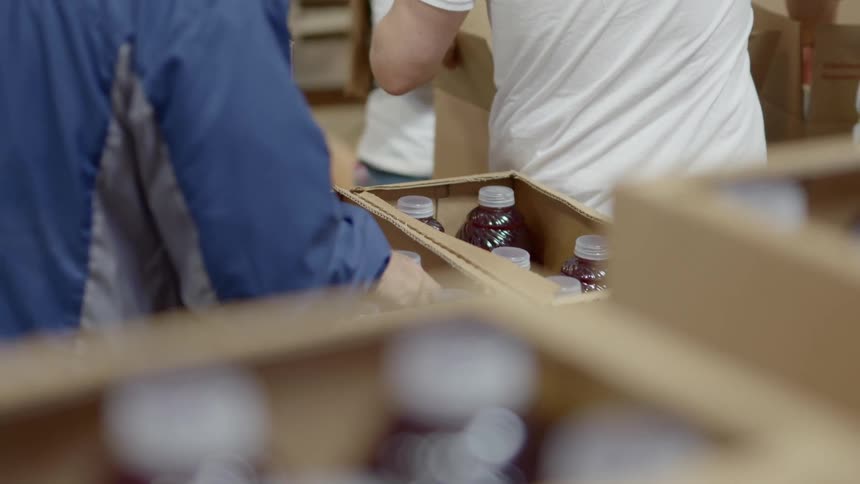 Workers filling cardboard boxes with groceries