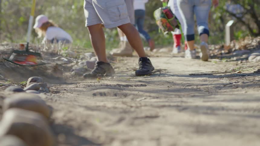 A group of people walk along a trail and clean up