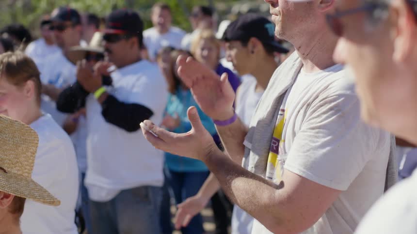 Crowd gathered outdoors clapping at day