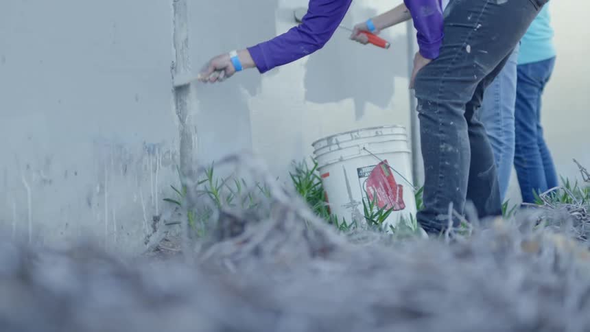 People paint wall with paint brush roll and brushes outdoors