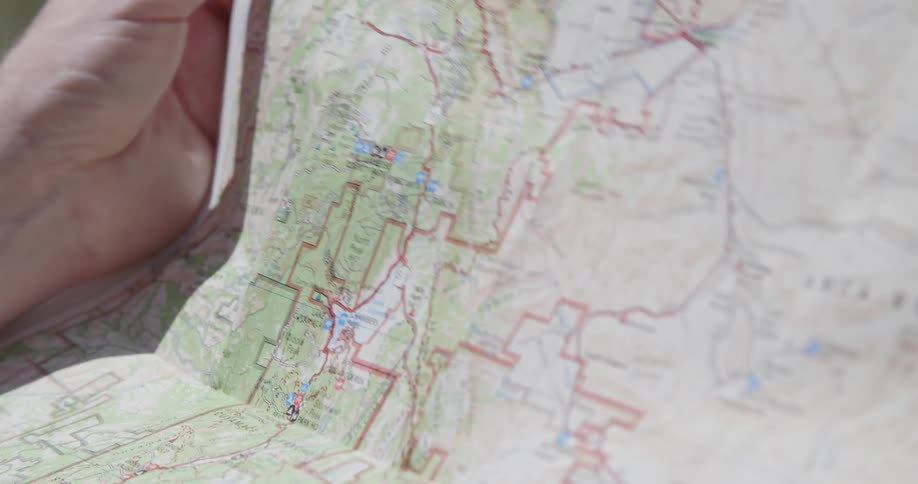 A white man holds a map and then folds it in half