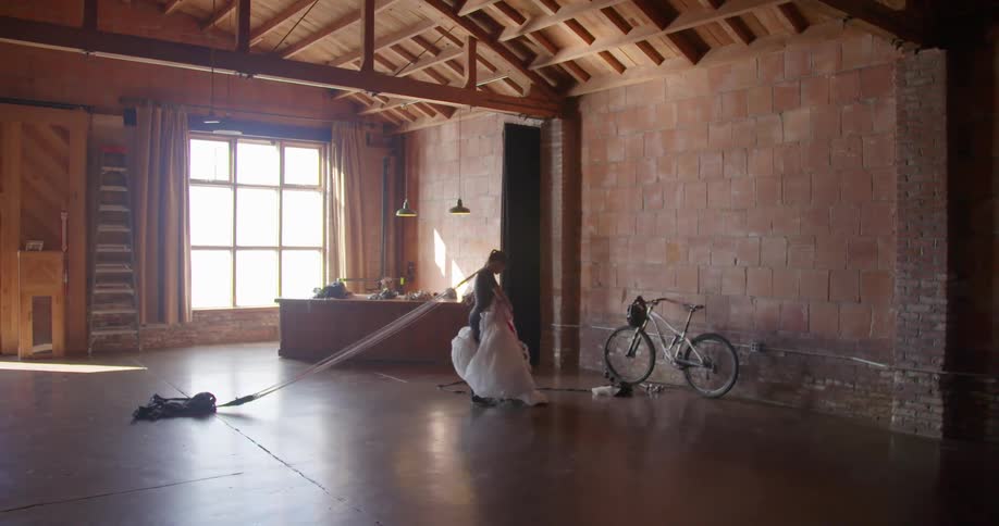 A woman stands in an empty house under construction holding something