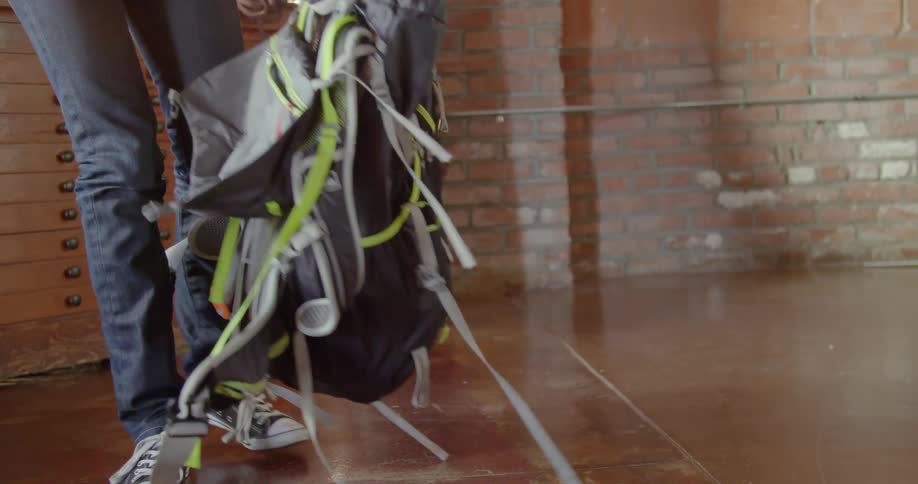 A woman gathers up the flaps and picks her backpack up off the floor and walks away