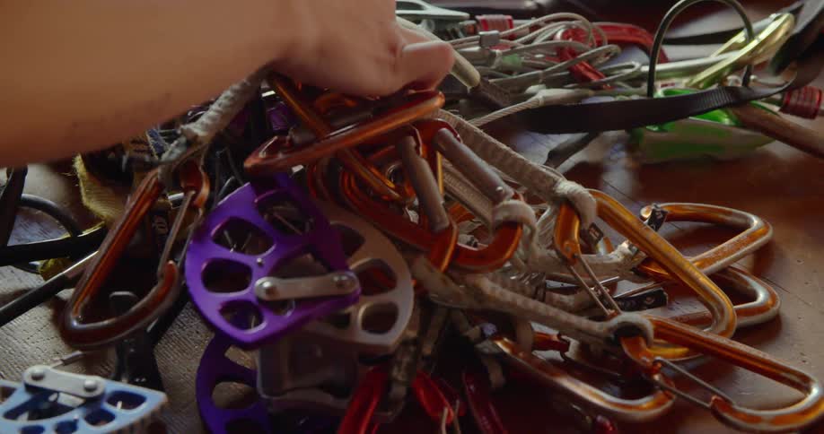 A person looks at a pile of ropes and clamps