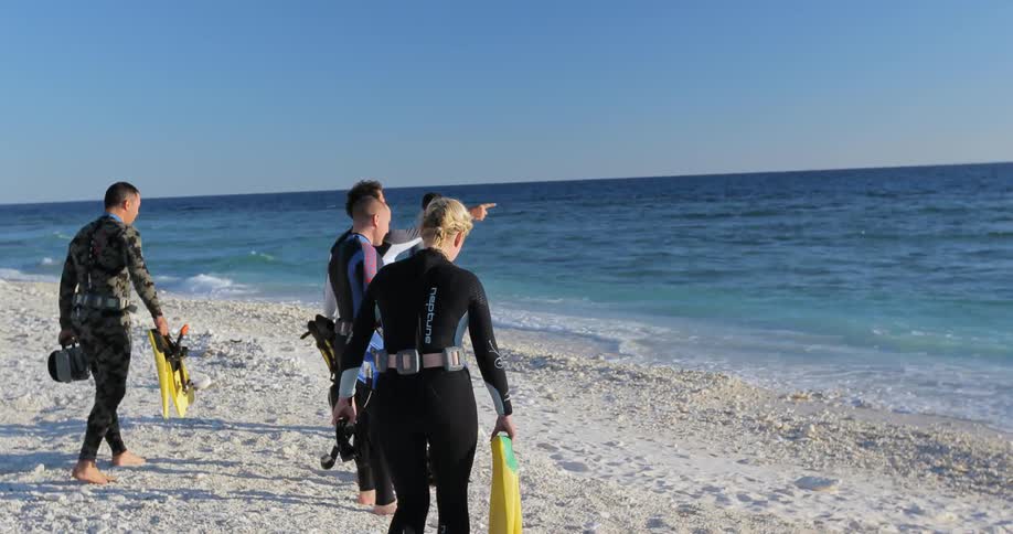 A group of people in wet suits get ready to go in the water