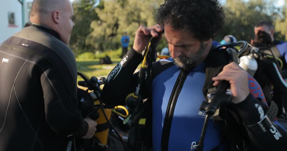 Divers donning and adjusting their equipment while still on land