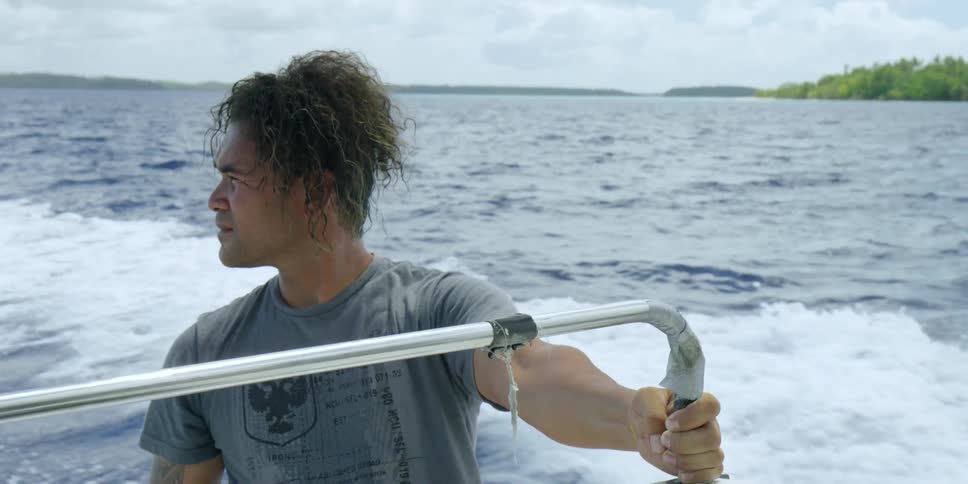 A man on a boat looks around and behind him