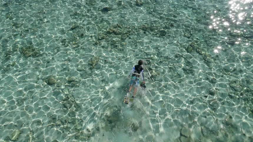 A person is swimming in the water holding a camera