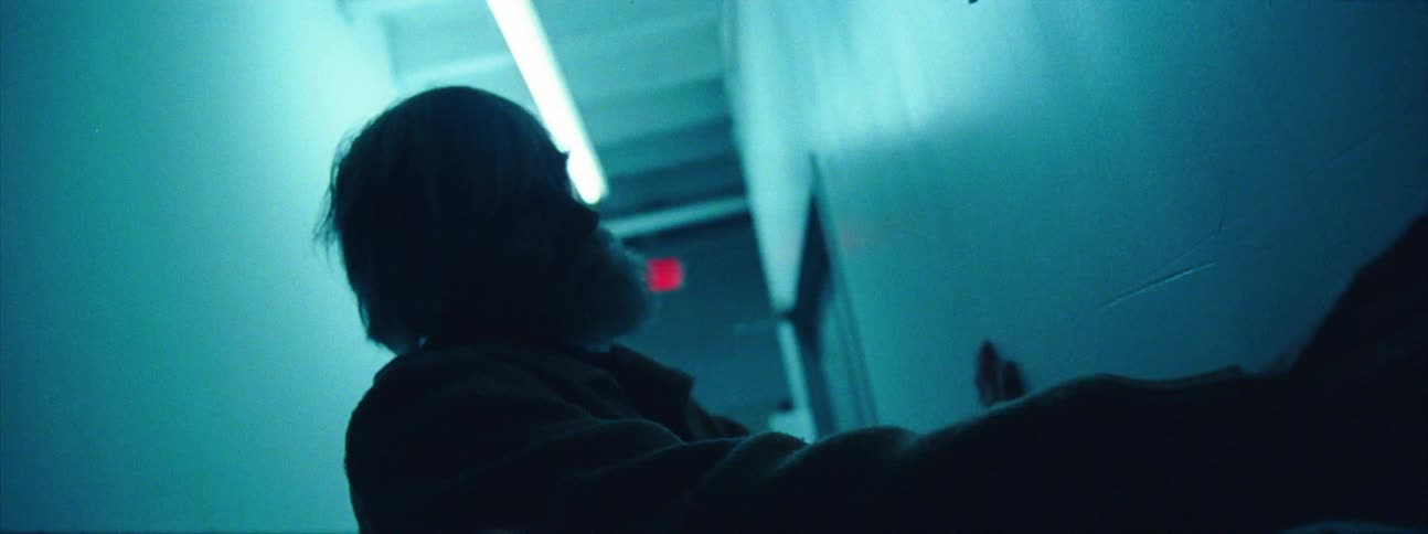A man in a hallway leaning and turning up against a wall