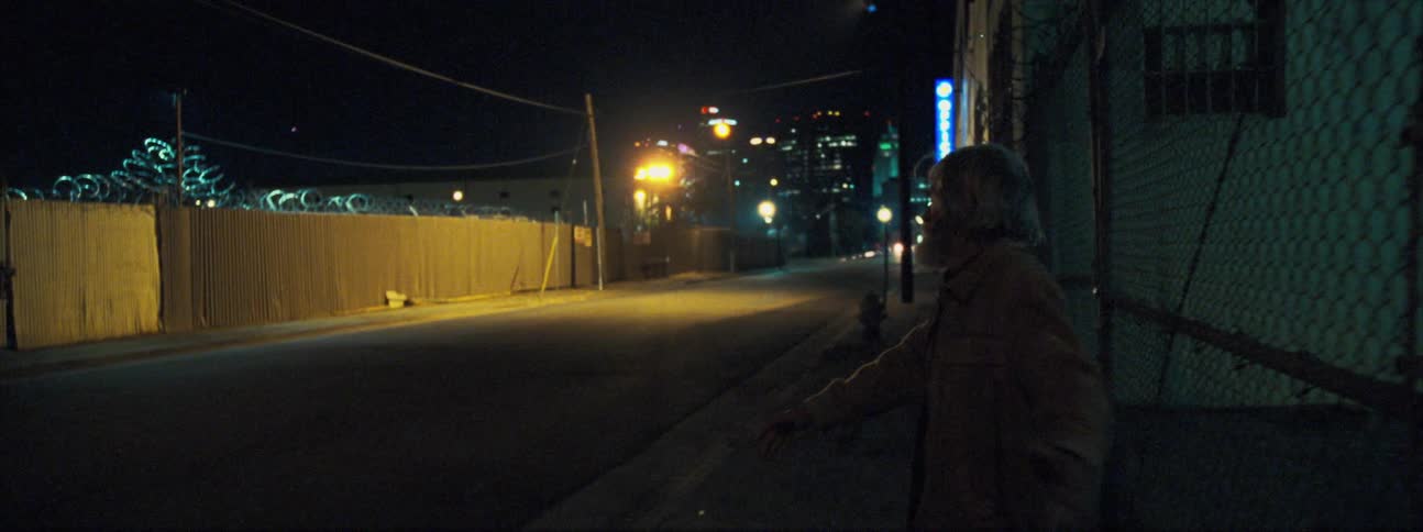 An elderly man twirls around by himself on a city street