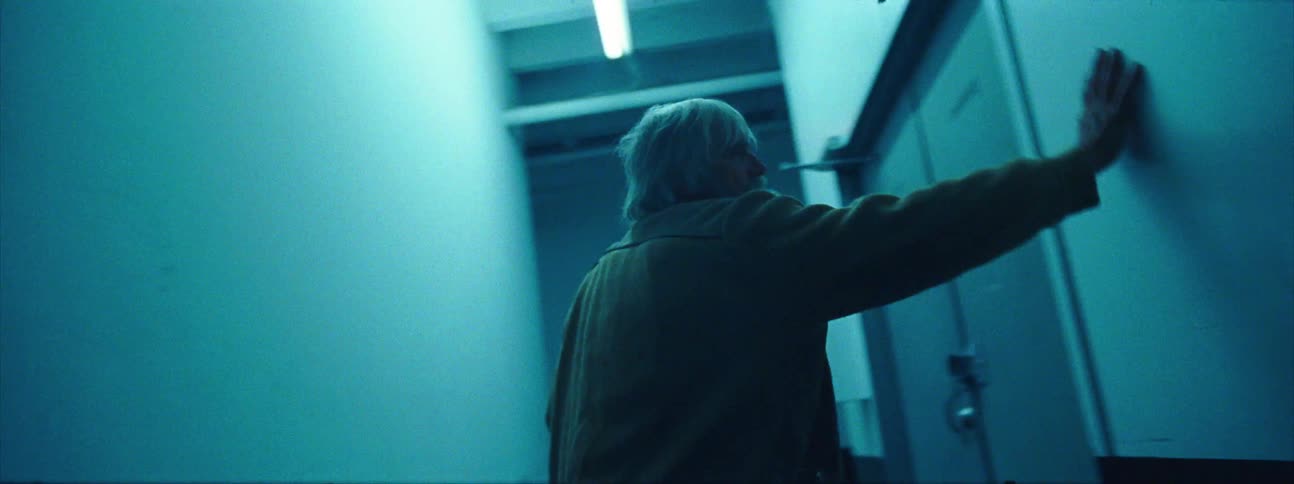 A man leaning and turning up against walls in a hallway