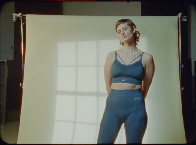 A woman stands in front of a photography back drop wearing athletic clothes
