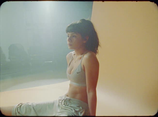 A woman sitting in front of a orange screen breathing deeply and taking pictures