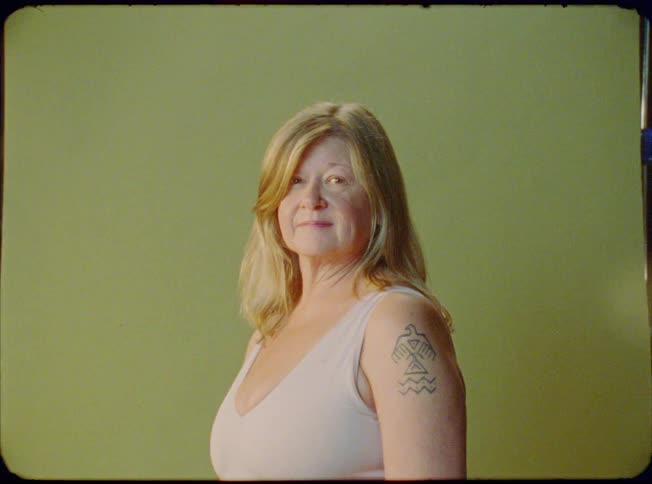 A woman poses for a photograph in front of a green backdrop