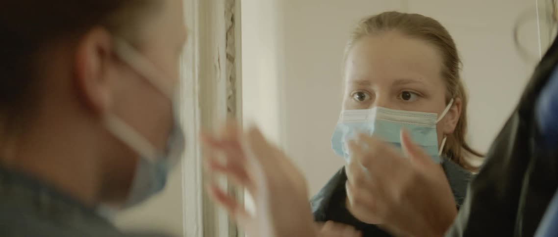 Woman looking in the mirror wears a face mask and goes out of the house