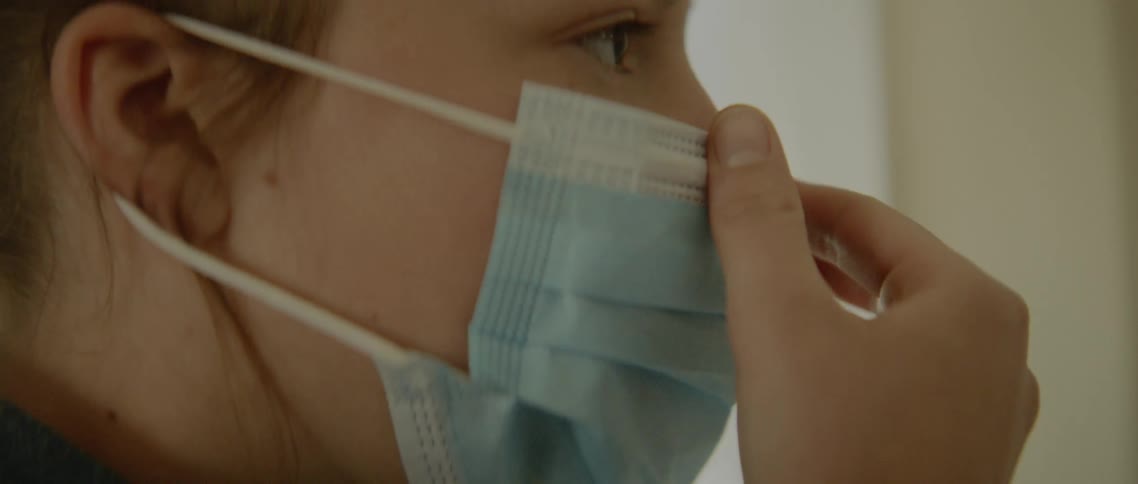 A nurse puts on a surgical mask