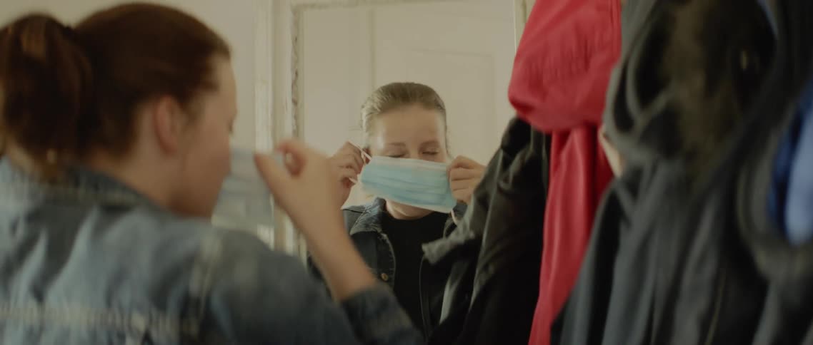 A girl puts on her jacket and then a mask