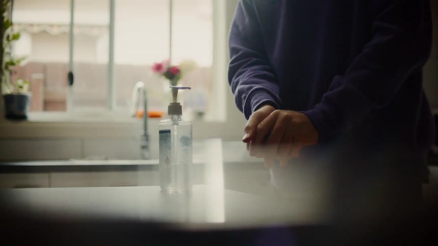 Person pumps hand sanitizer onto hands and rubs them