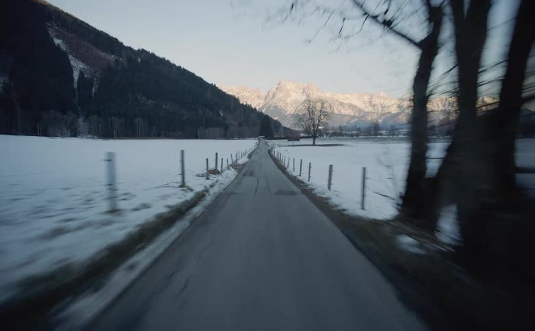 Vehicle drives along the narrow road between snowy farmlands