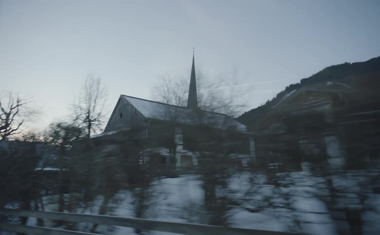 Driving fast on country road next to church on snowy landscape