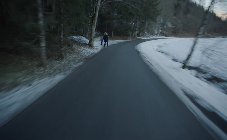 People walking along the side of a quiet road with mountains in the background