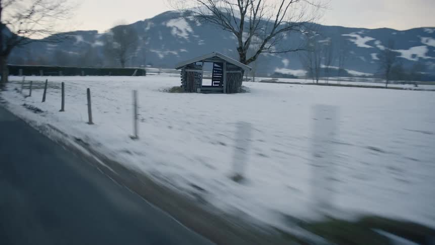 Passing by a snow covered field with a wobbly wooden shack heading towards mountains