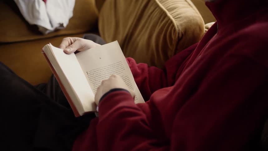 Person sits on the couch reading a book