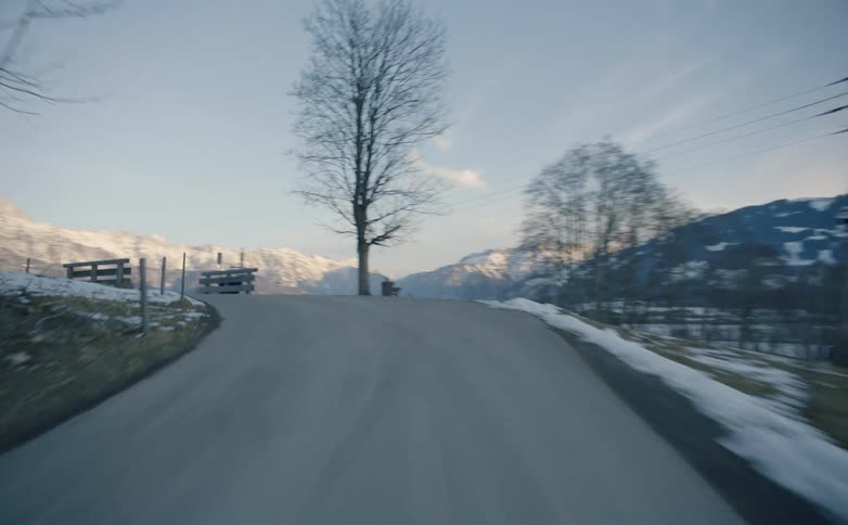 Vehicle drives along winding narrow road in the snowy hills