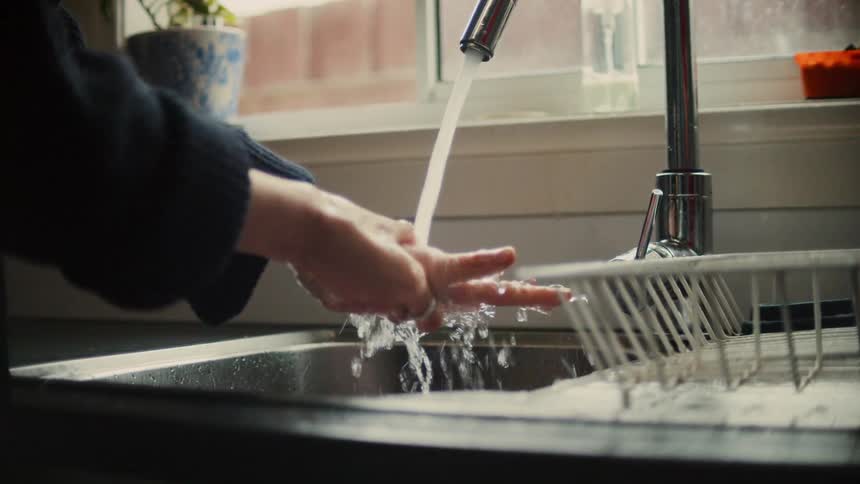 Woman washes her hands in the kitchen