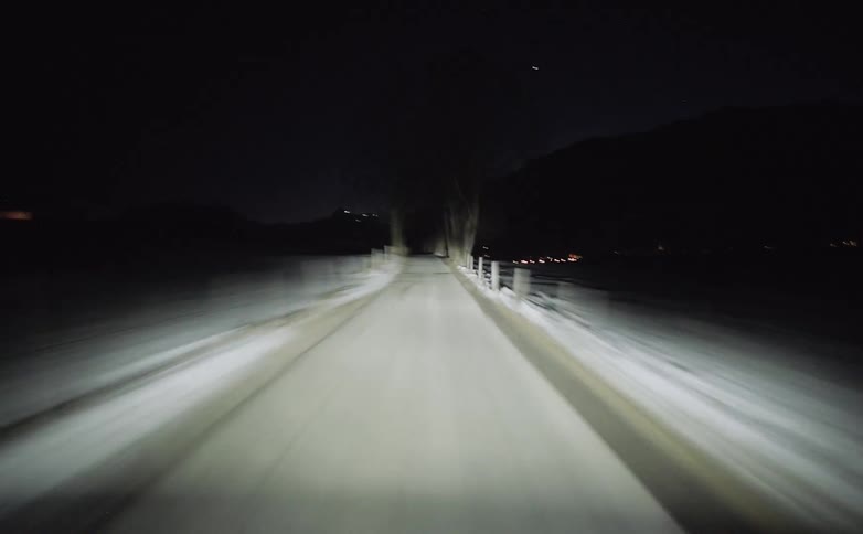 Speeding down a narrow rural road with snow and trees on the roadside