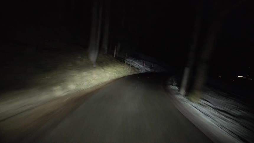 Driving fast on country road through snow covered landscape at night