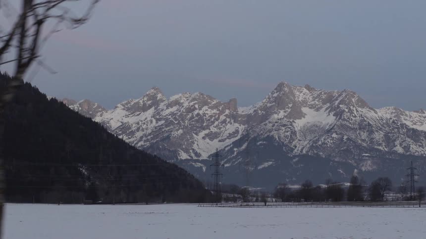 A snowy landscape with snow capped mountains in the distance