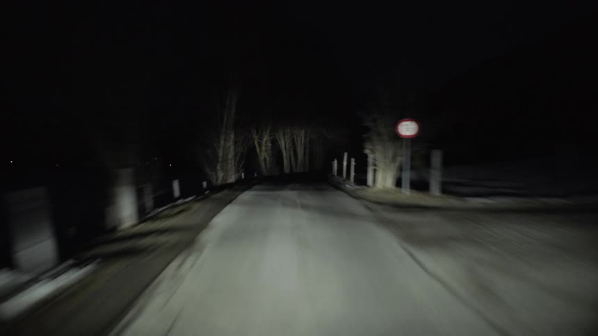 Driving on a road through a rural area at night in the winter
