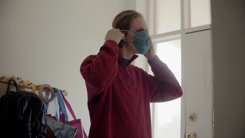 A male teenager puts a mask on