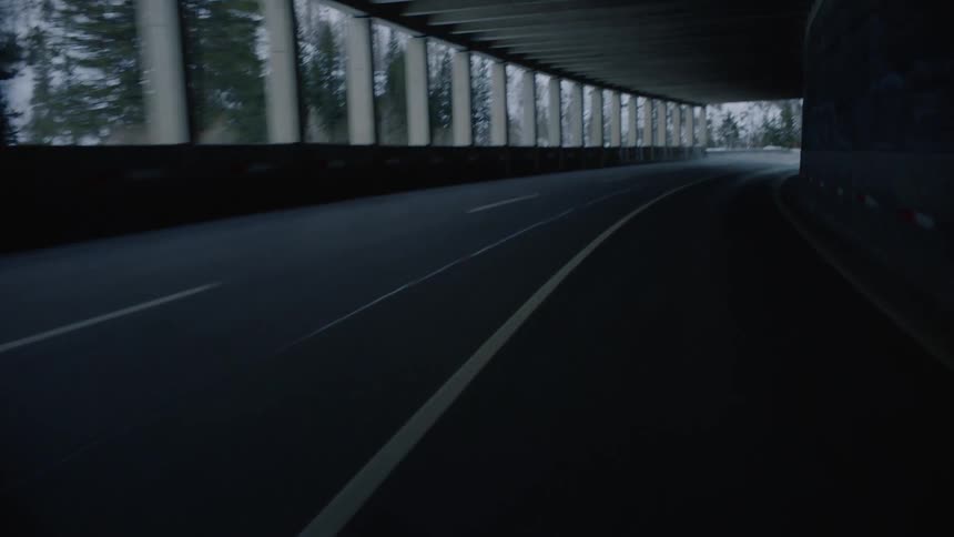 Driving along covered curving road near snowy mountains