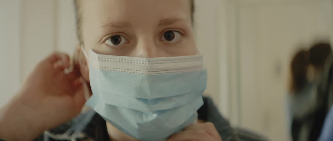 Close up of woman putting on medical face mask then walking away