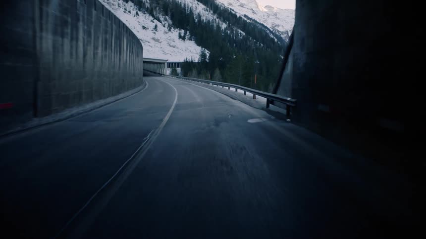 Driving through a dark tunnel on a mountain road in the winter
